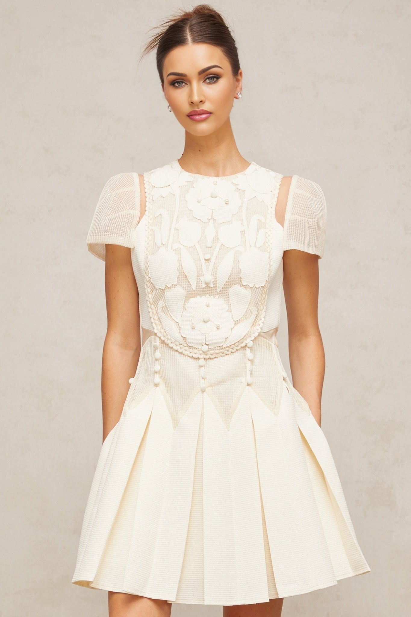 A white mini dress featuring delicate flower embroidery details throughout the fabric