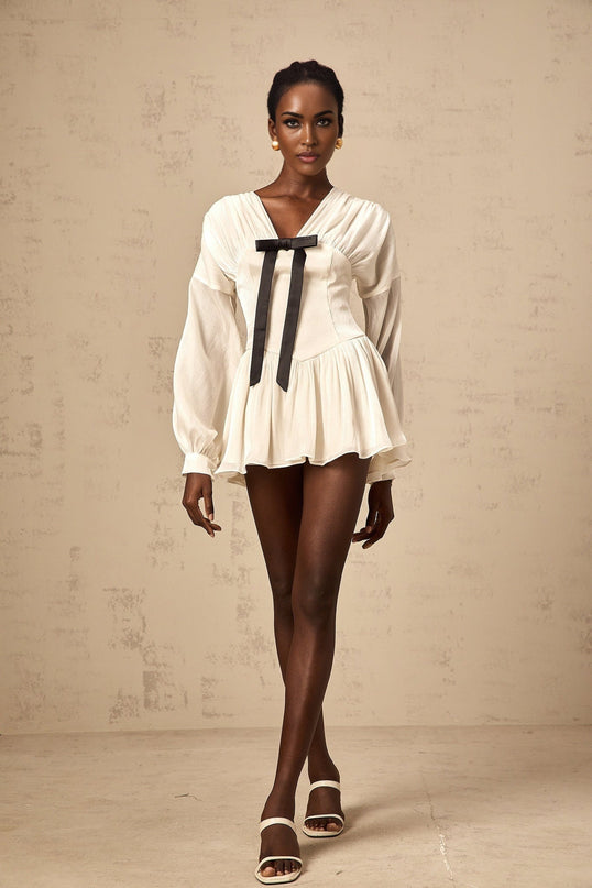 A white mini dress with a bowknot detail and glitter accents called the Lina dress