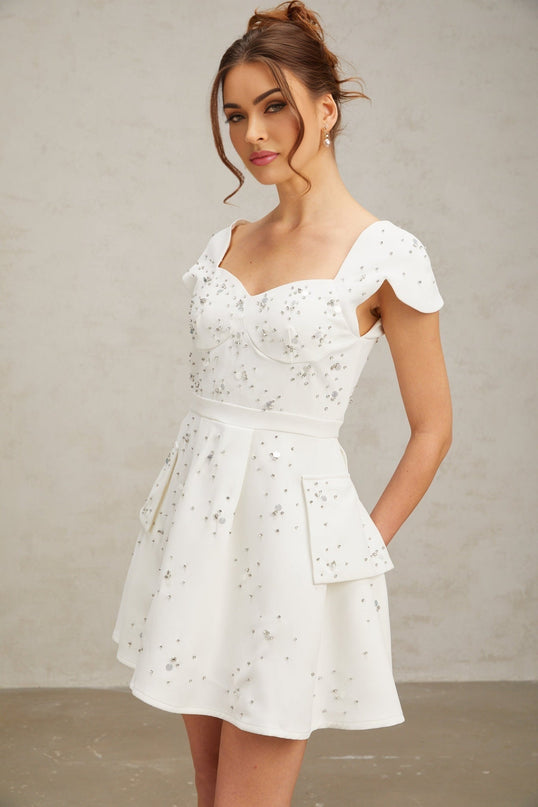 A white mini dress with a flared skirt and embellished details worn by a model named Bonnie