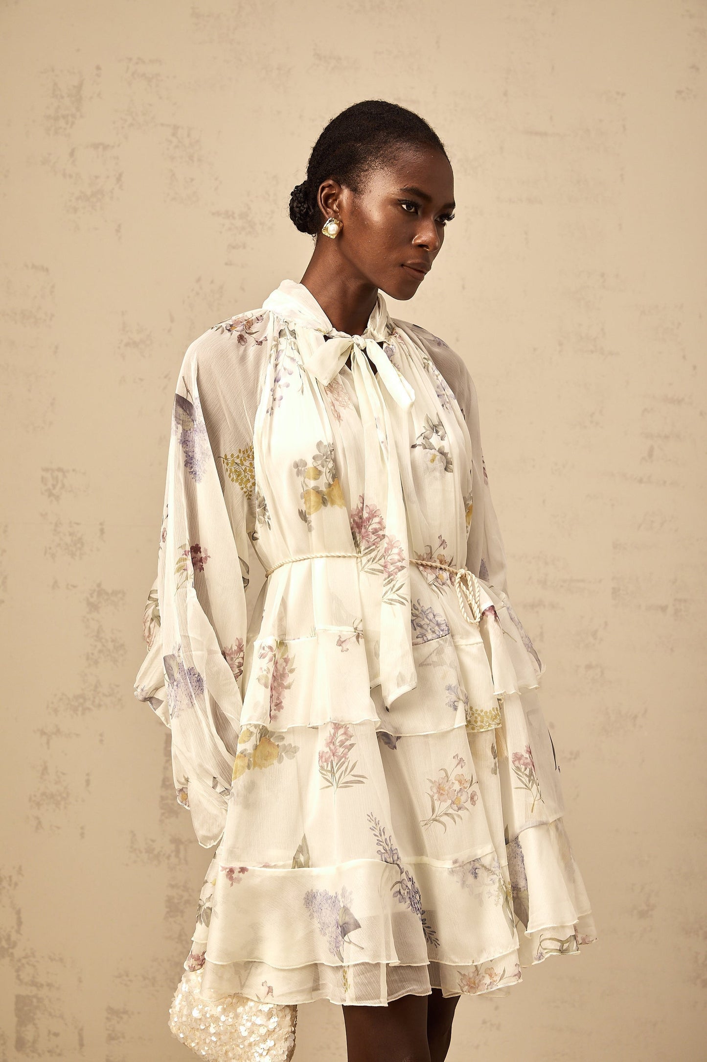 A white mini dress with a floral print pattern made from tiered chiffon fabric featuring a short length and light airy design