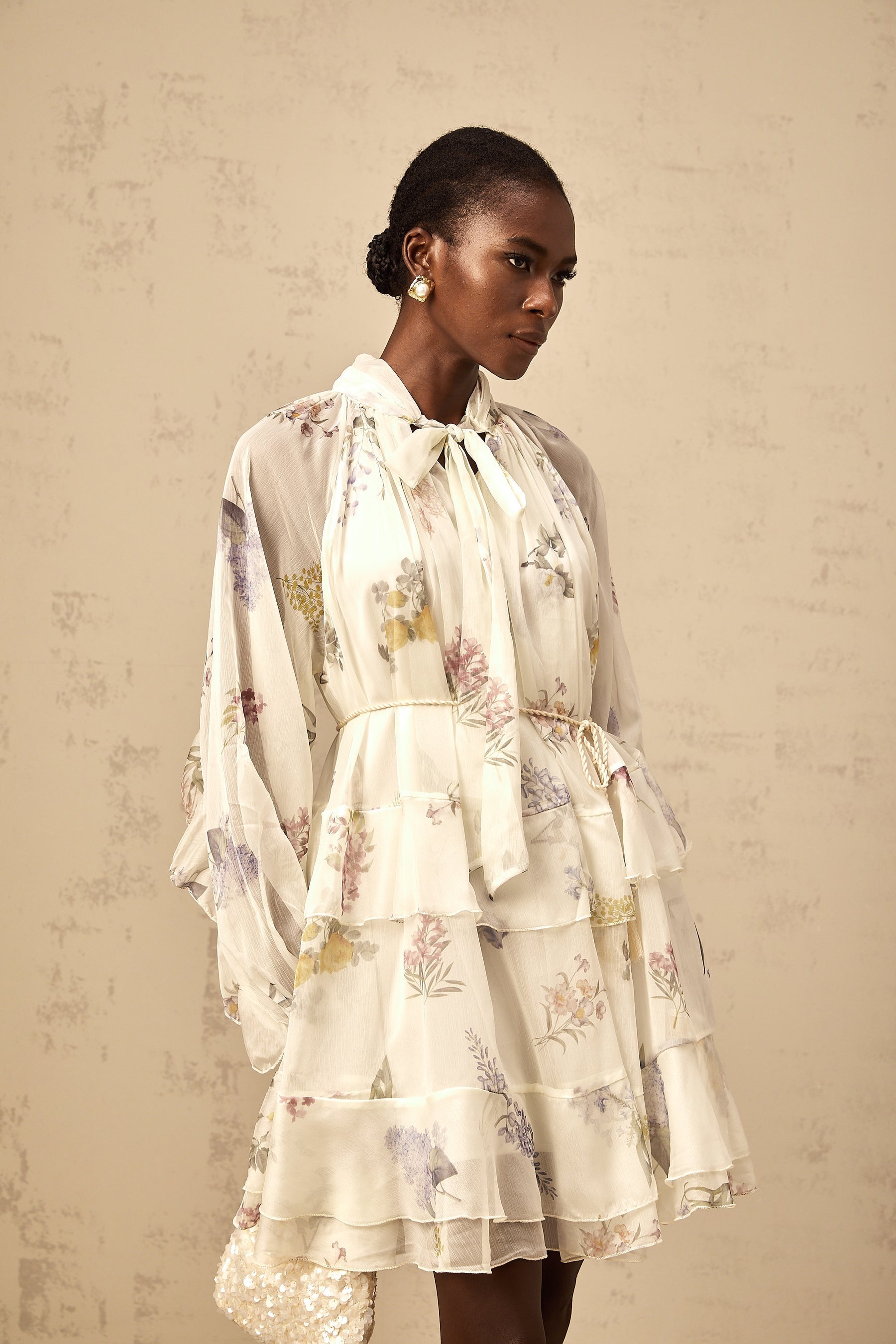 A white mini dress with a floral print pattern made from tiered chiffon fabric featuring a short length and light airy design