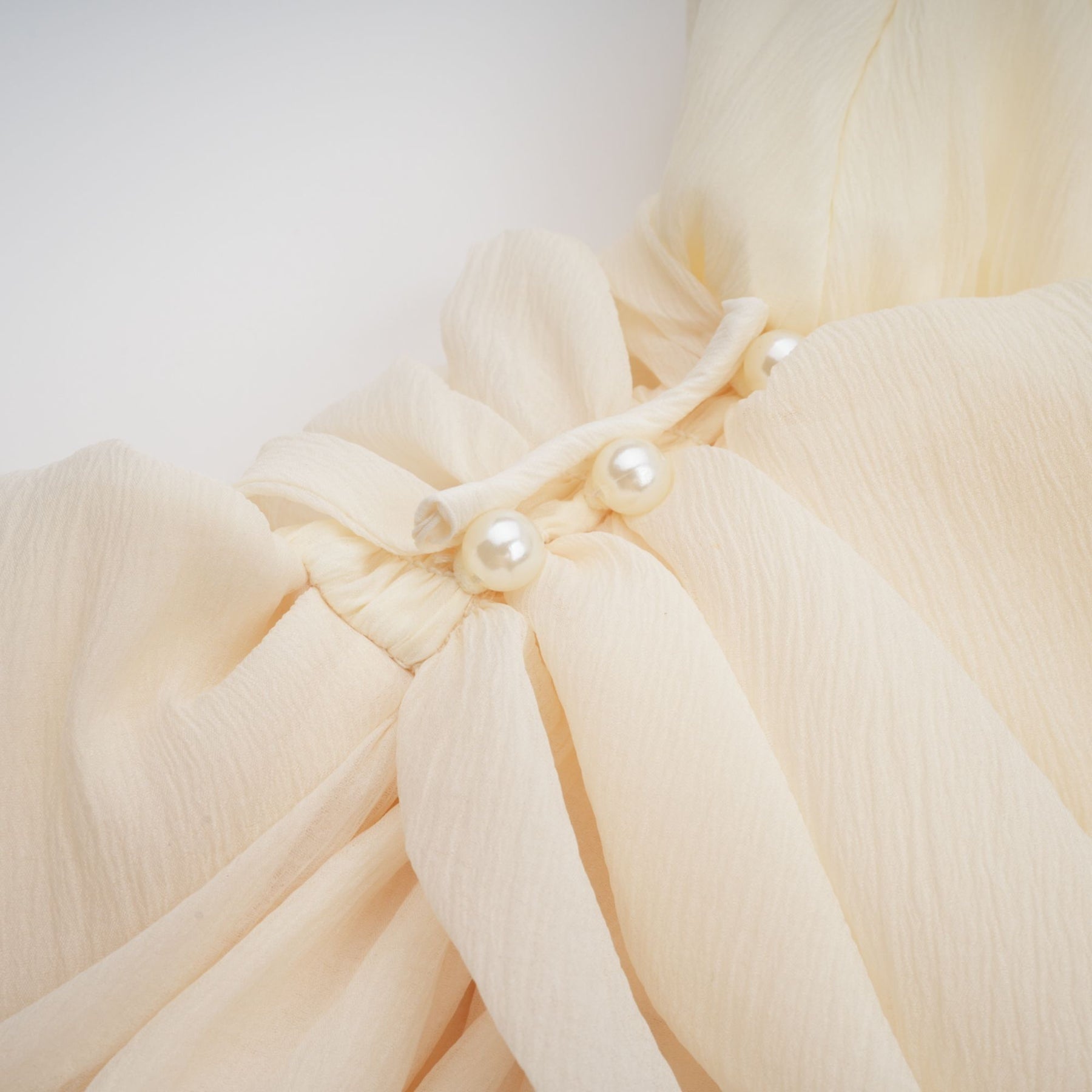 A white mini dress with a halterneck style adorned with faux pearls named Berenice