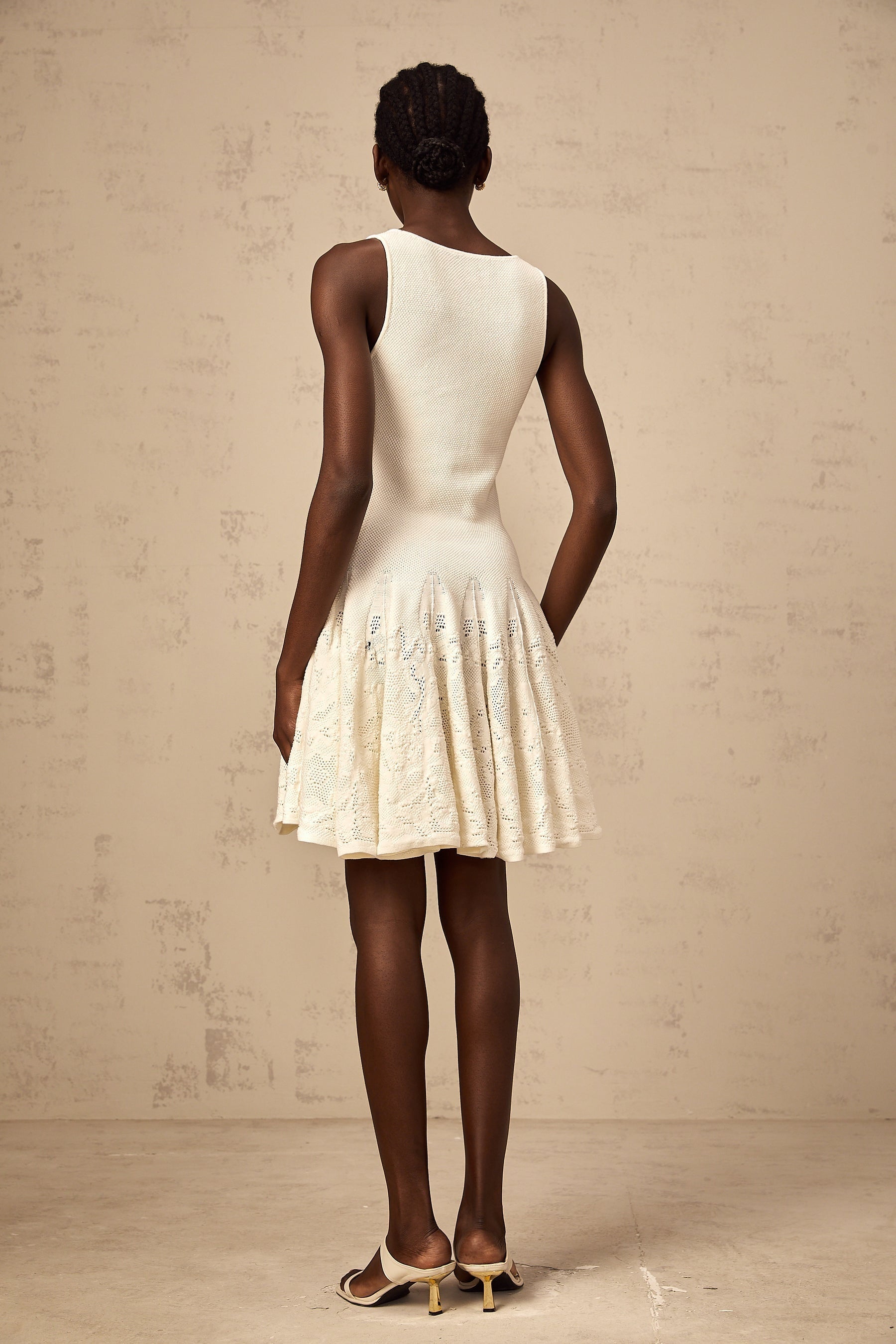 A white mini dress with a jacquard knit pattern featuring a short hemline and textured fabric design