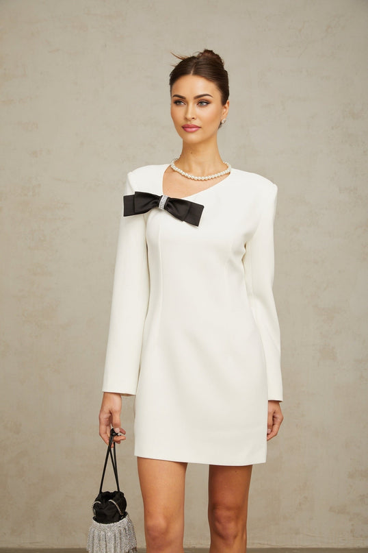 A white mini dress with an asymmetric hemline and a decorative bowknot detail named Colette