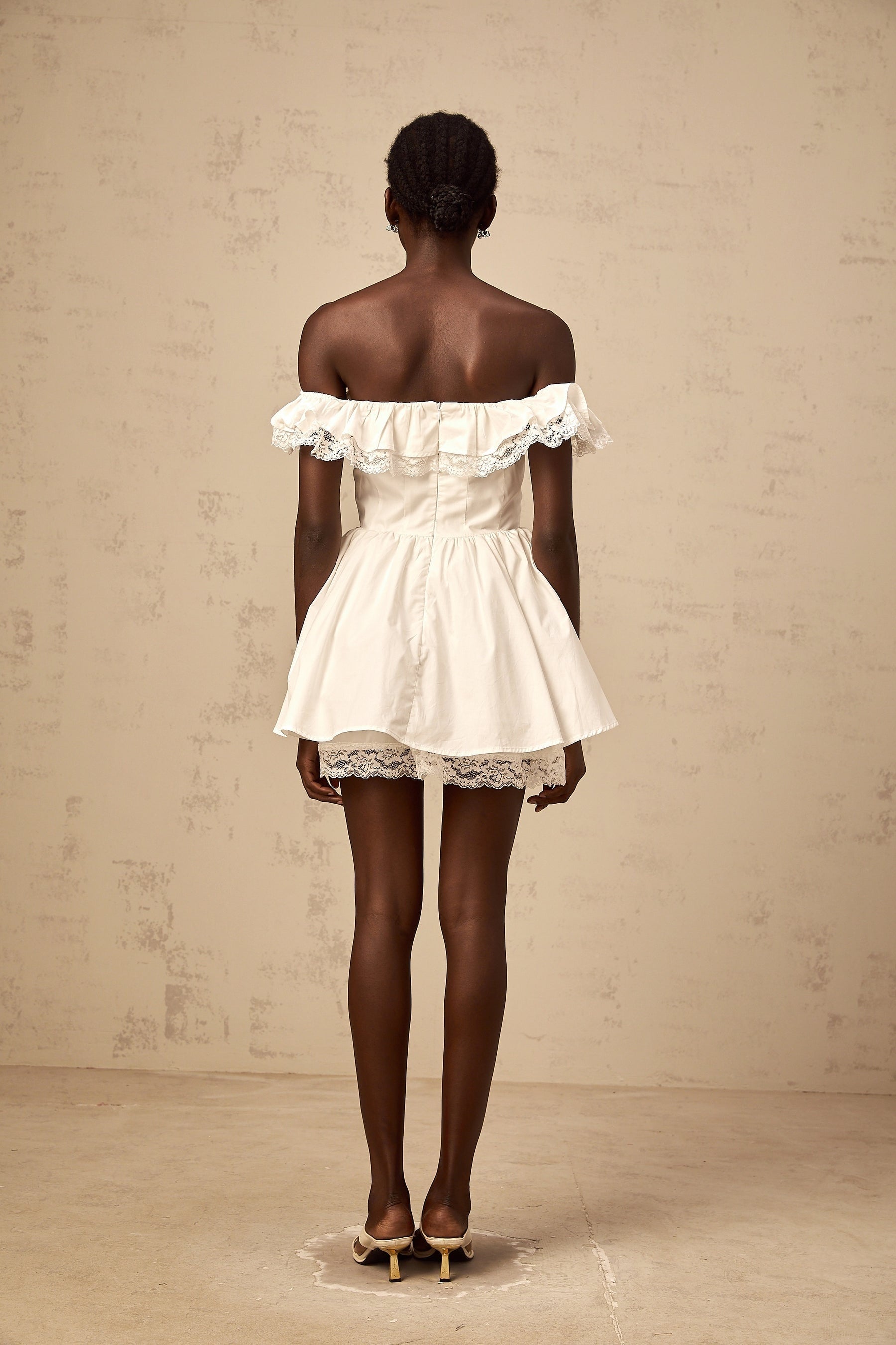A white mini dress with an oversized bow and ruffle details featuring a short hemline and feminine silhouette