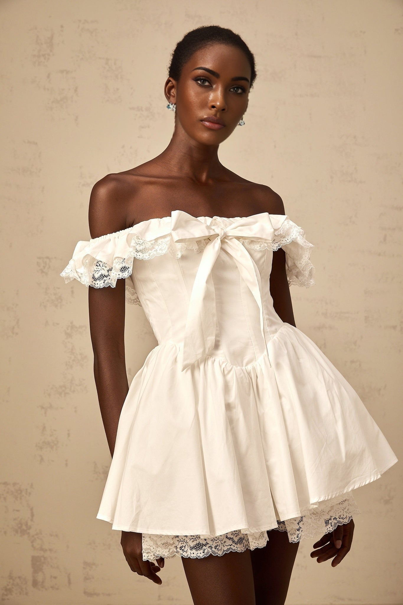 A white mini dress with an oversized bow and ruffled details featuring a loose fit and short length