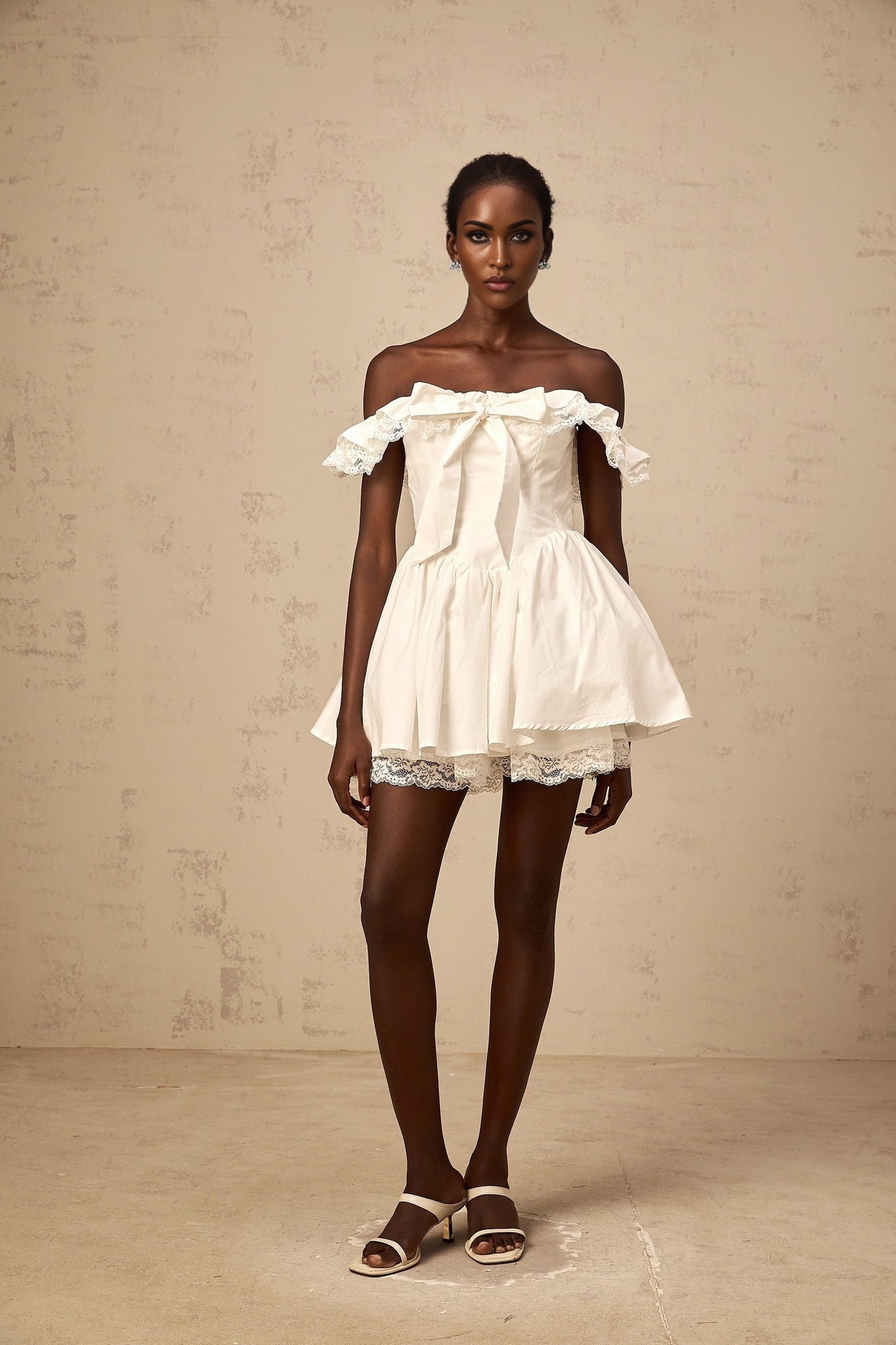 A white mini dress with an oversized bow and ruffled details featuring a short hemline and feminine silhouette