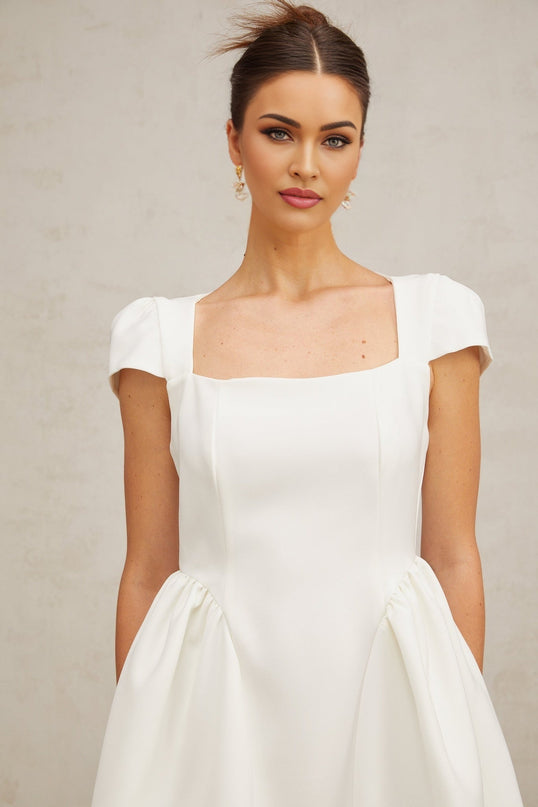 A white mini dress with cap sleeves featuring a fitted silhouette and a short hemline The dress has a simple elegant design suitable for summer or formal occasions