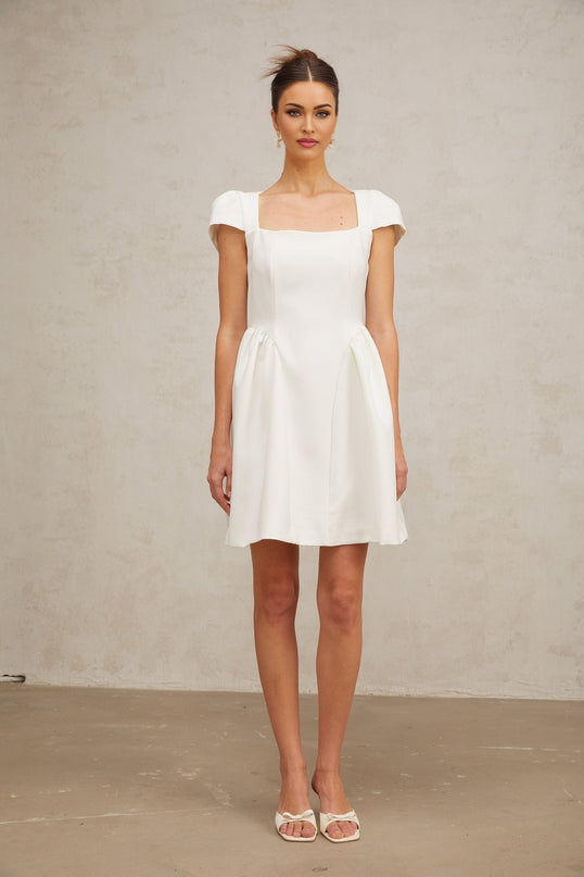 A white mini dress with cap sleeves featuring a fitted silhouette and a short hemline