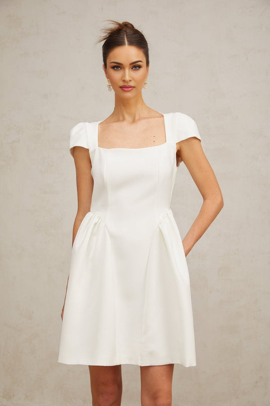 A white mini dress with cap sleeves featuring a slim fit silhouette and a short hemline perfect for a summery or elegant look
