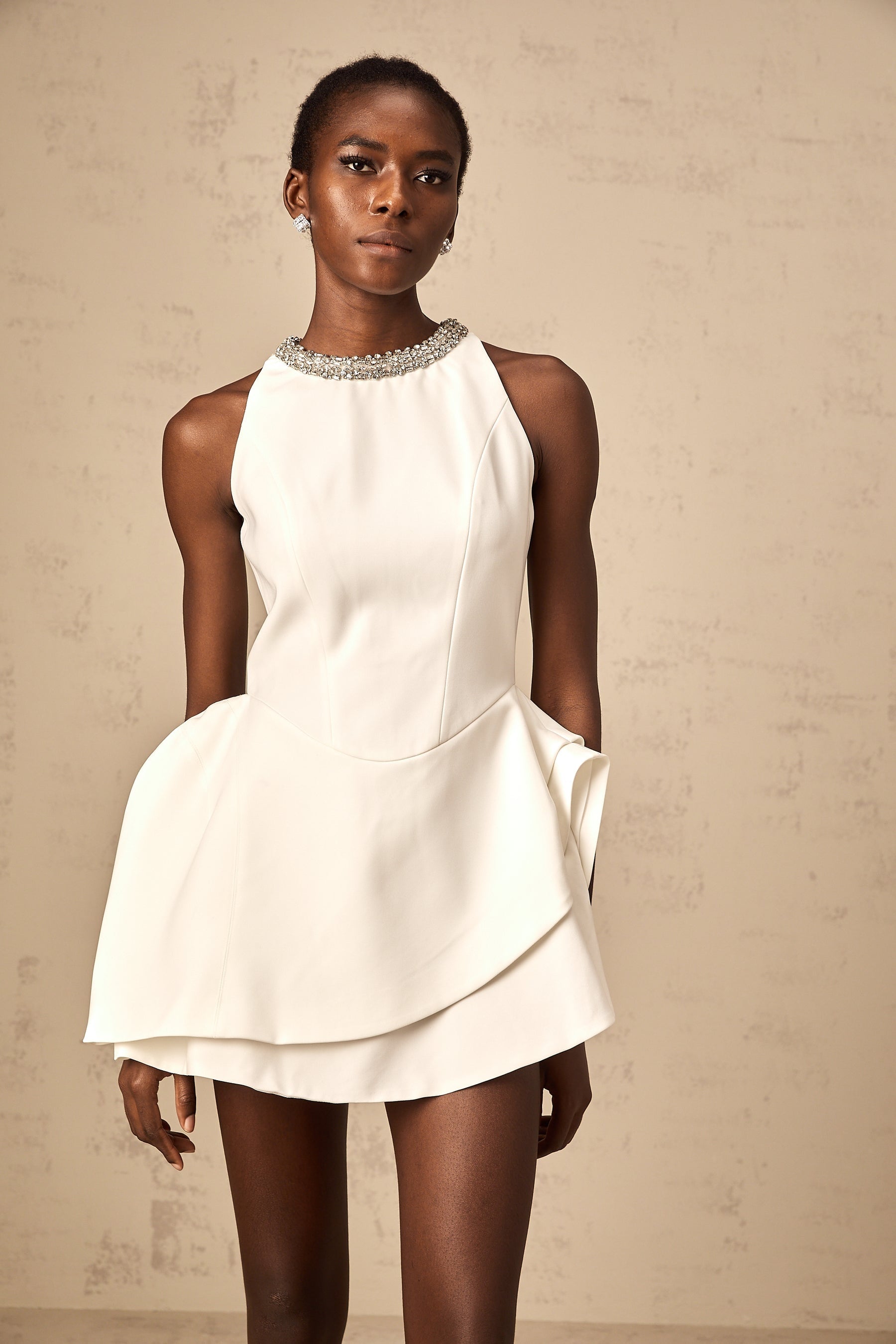 A white mini dress with crystal embellishments and layered design worn by a model named Denise
