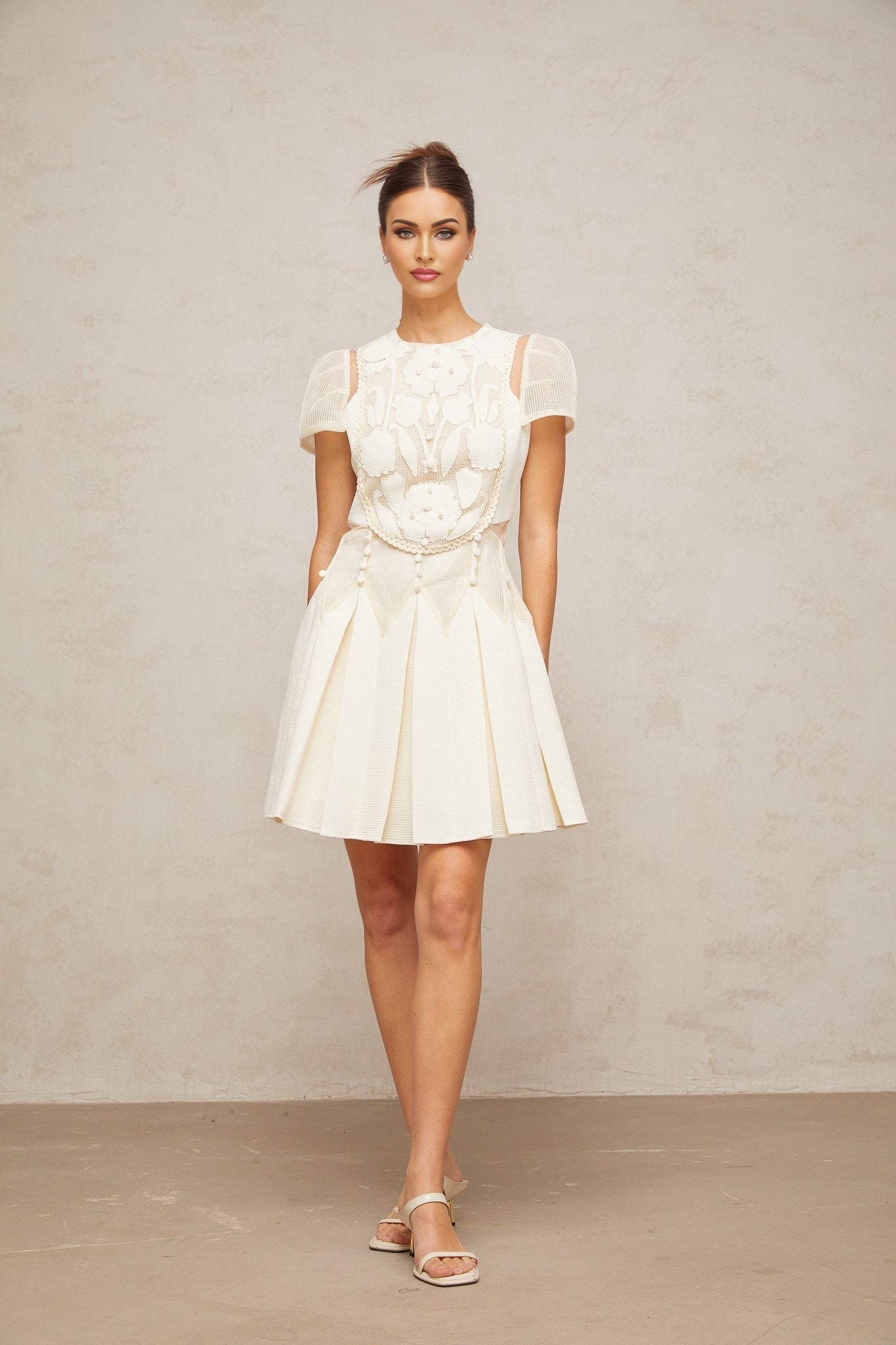 A white mini dress with delicate flower embroidery details covering the fabric Maelle brand