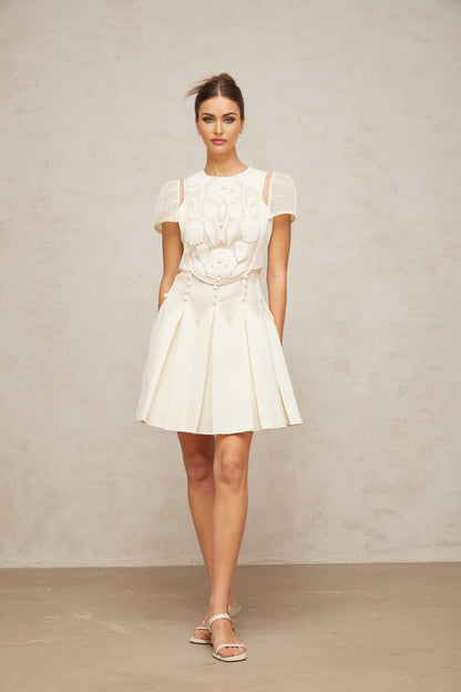 A white mini dress with delicate flower embroidery details covering the fabric Maelle brand
