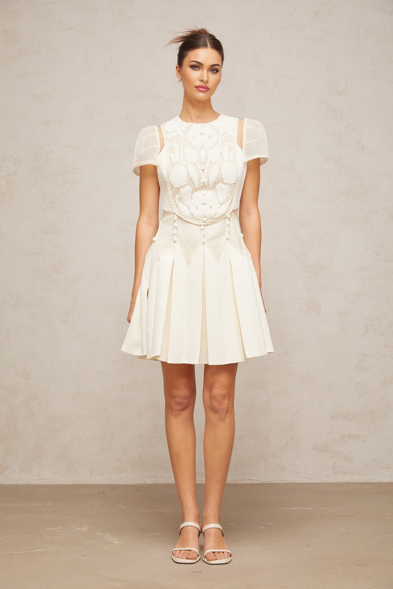 A white mini dress with delicate flower embroidery pattern adorning the fabric