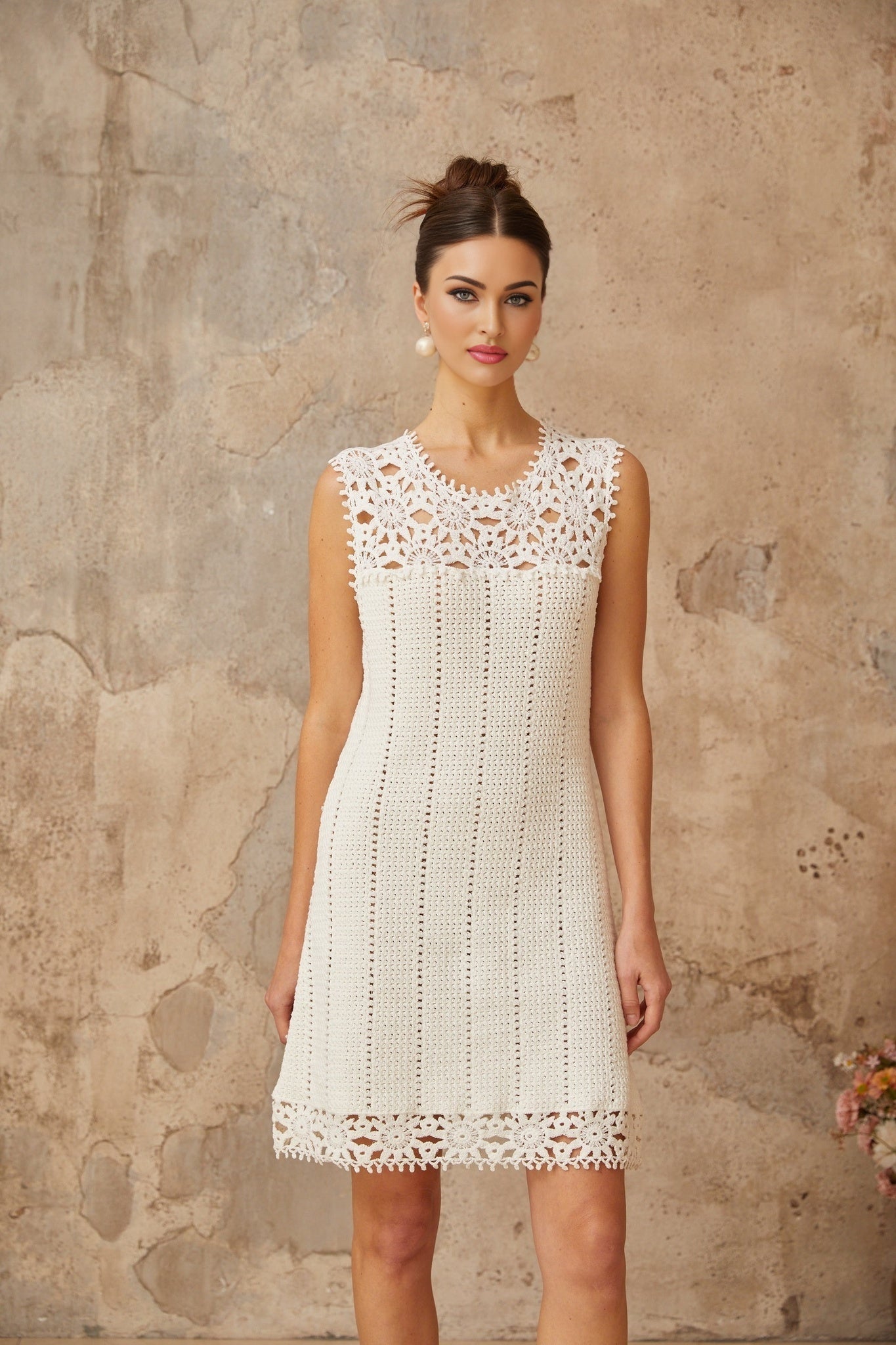 A white mini dress with floral applique detailing and crochet knit texture