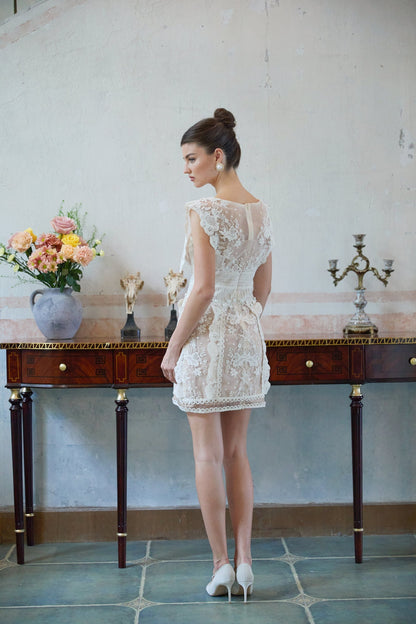 A white mini dress with floral embroidery and lace detailing featuring a short hemline and delicate feminine design