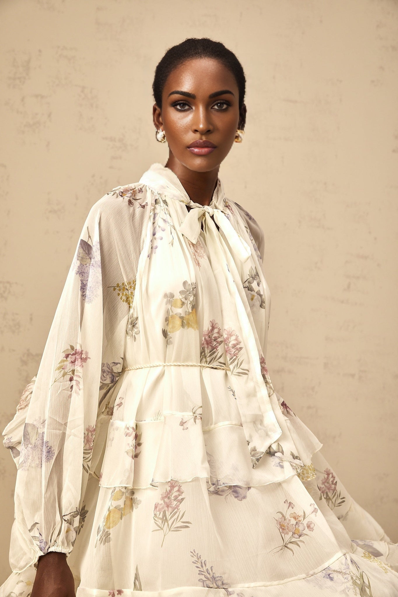 A white mini dress with floral print made of tiered chiffon fabric featuring a delicate and feminine design
