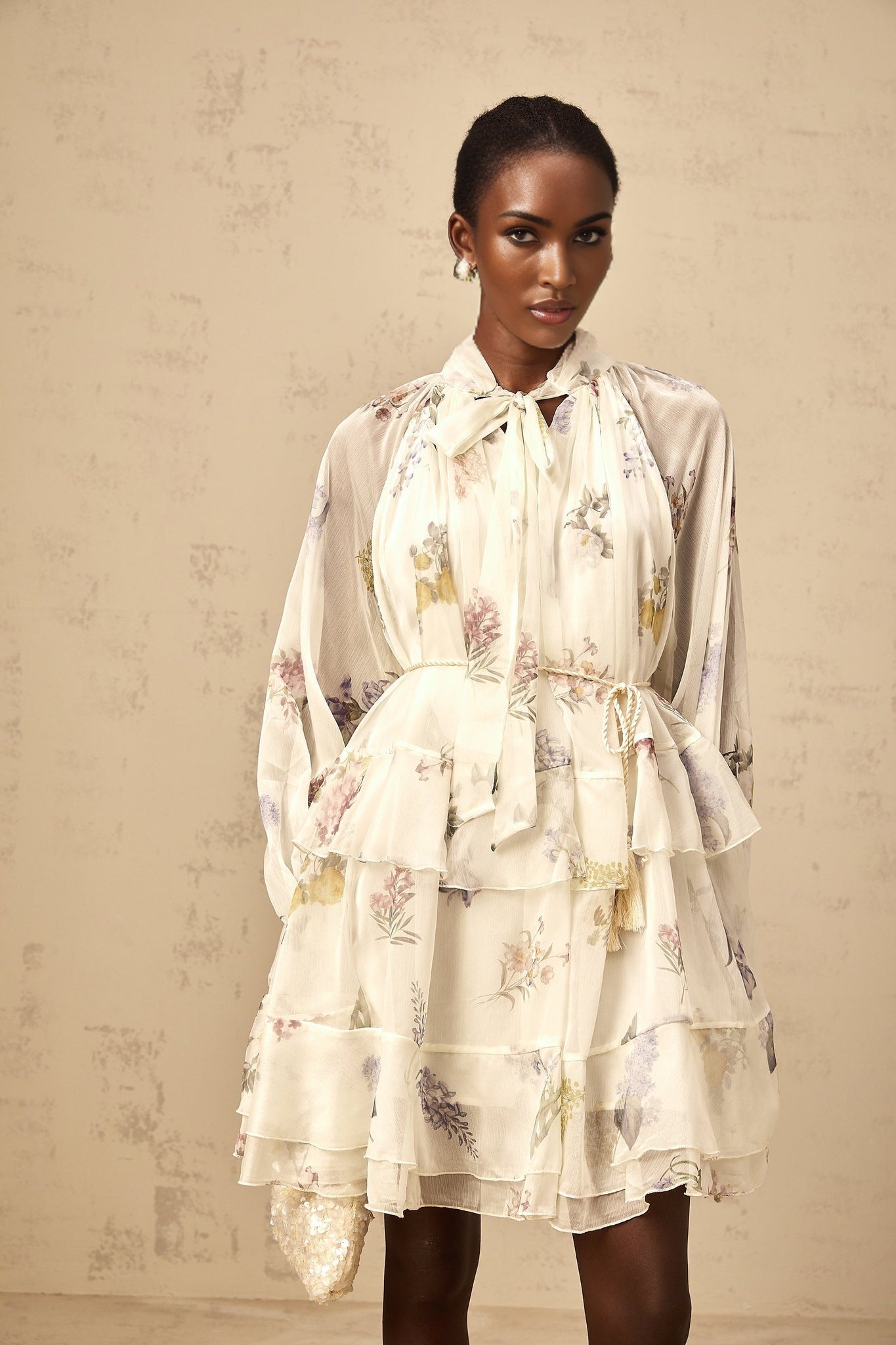 A white mini dress with floral print pattern made of tiered chiffon fabric featuring a short length and lightweight flowing design
