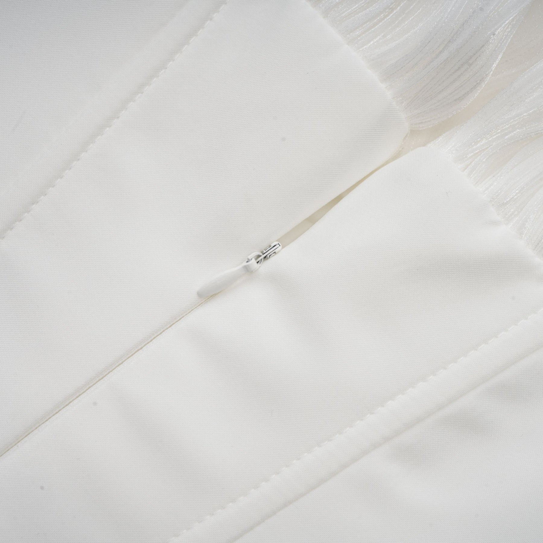 A white mini dress with full pleating and a cinched waist featuring a rosier design