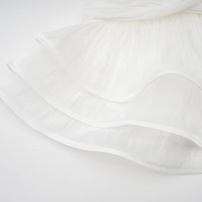 A white mini dress with full pleats and a cinched waist featuring a rosier design on a model against a plain background