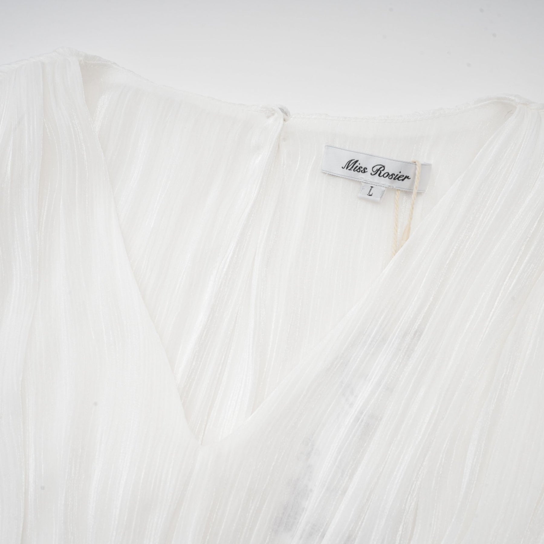 A white mini dress with full pleats and a cinched waist featuring a rosier design