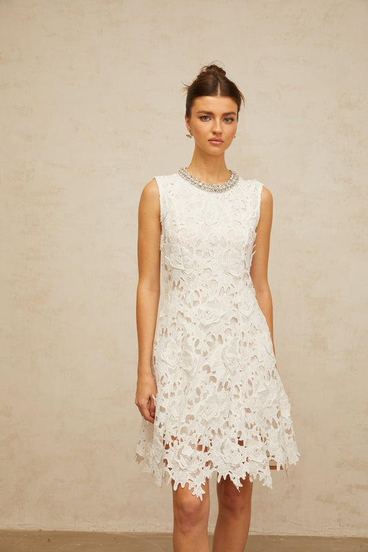 A white mini dress with intricate embellished corded lace detailing featuring a short hemline and delicate feminine design