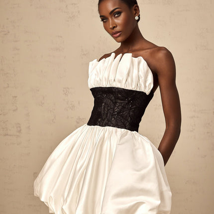 A white mini dress with puff sleeves and lace panels made from satin fabric