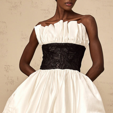 A white mini dress with puff sleeves featuring lace paneling and a satin finish