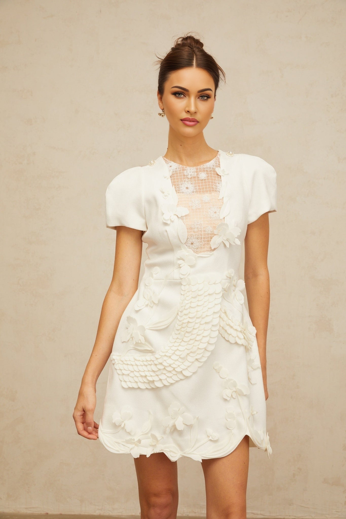A white mini dress with puffed sleeves and floral applique details