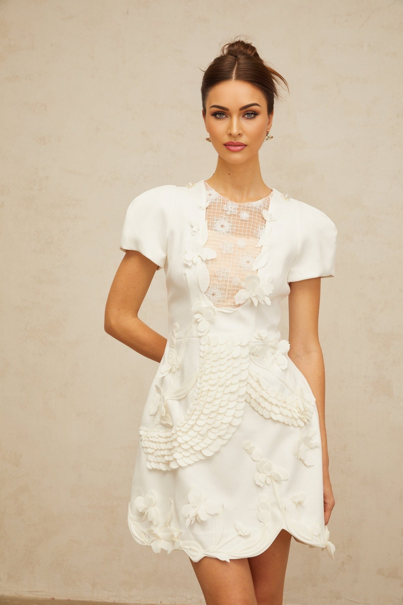 A white mini dress with puffed sleeves featuring floral applique details