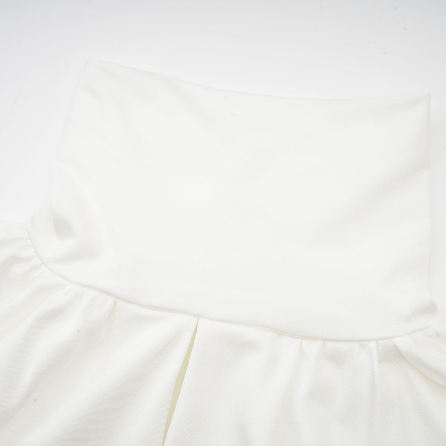 A white mini dress with ruched detailing and faux flower embellishments showcasing the Maeva design