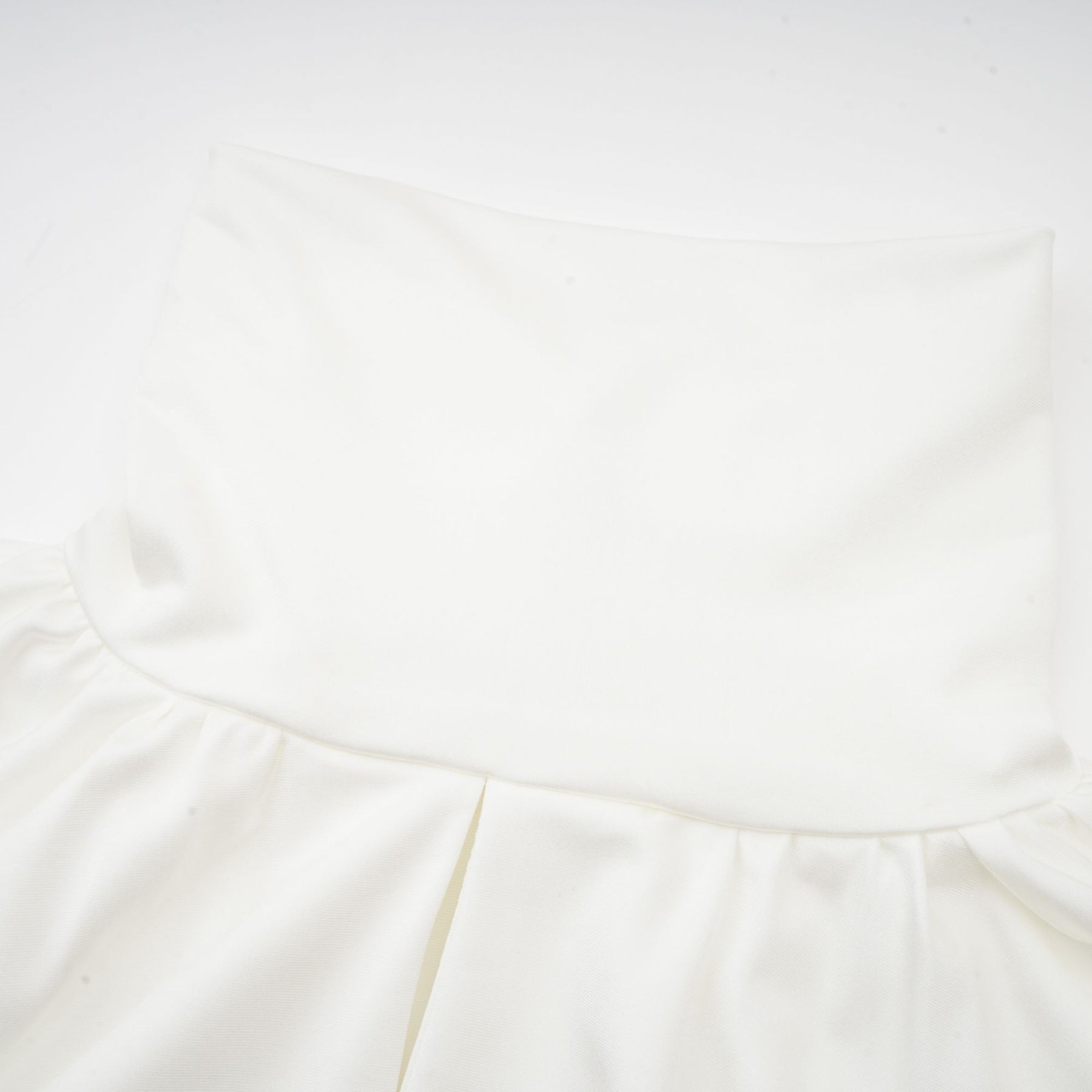 A white mini dress with ruched detailing and faux flower embellishments showcasing the Maeva design