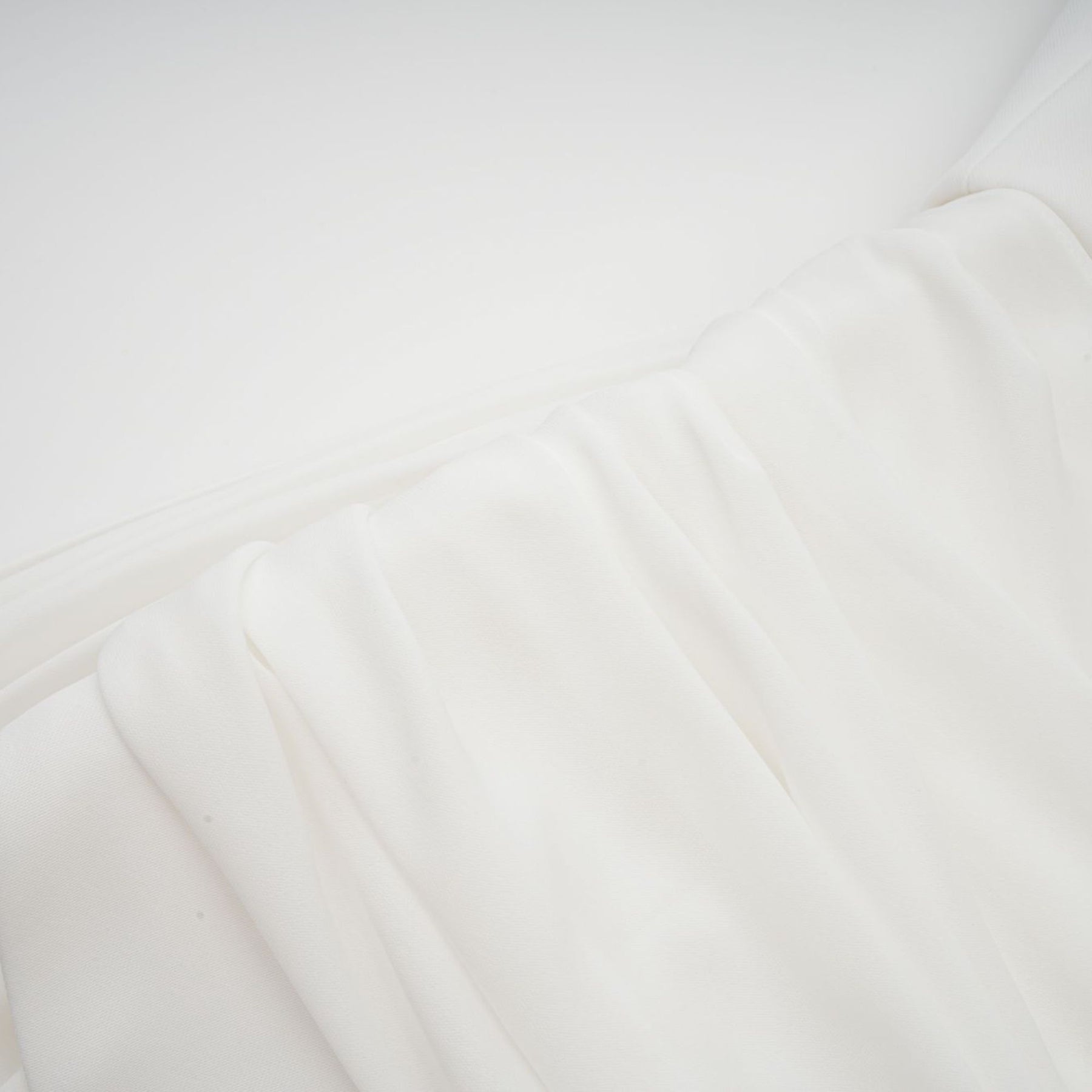 A white mini dress with ruched fabric and ribbon design details featuring a short hemline and fitted silhouette