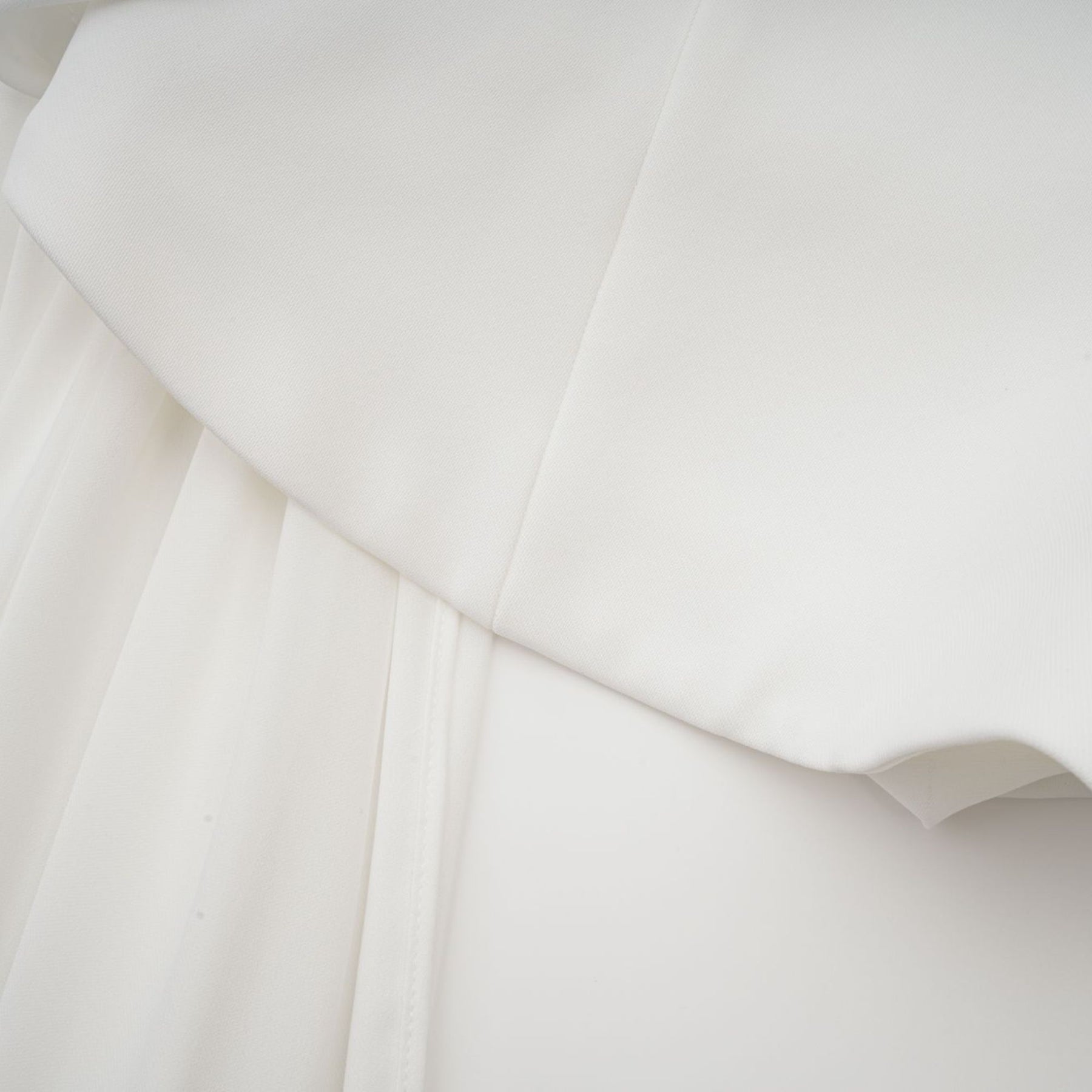 A white mini dress with ruched fabric and ribbon design details featuring a short hemline and formfitting silhouette
