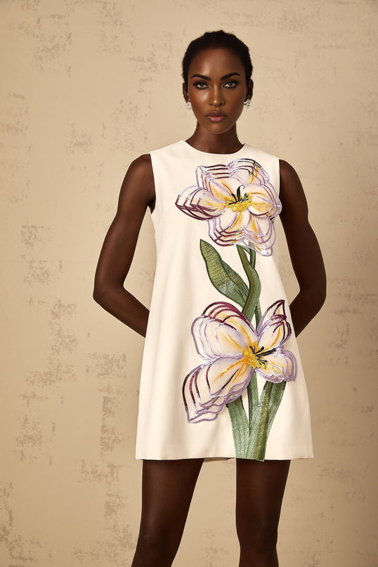 A white mini dress with sequin floral embroidery worn by a woman named Irene featuring a short hemline and intricate floral patterns