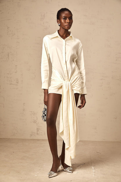 A white mini shirt dress with ruched detailing and ribbon accents named Daphne featuring a short length and buttonup design