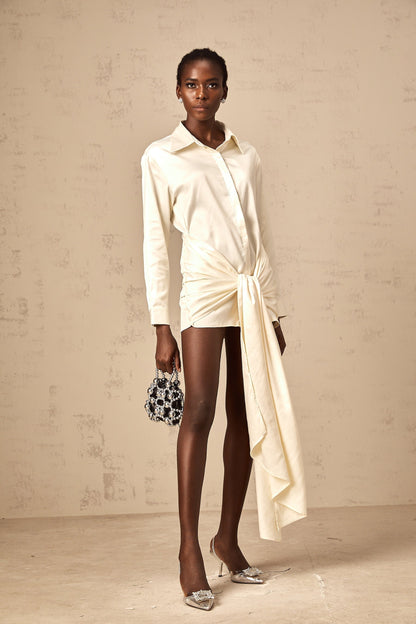 A white mini shirt dress with ruched detailing and ribbon accents named Daphné featuring a short length and feminine design