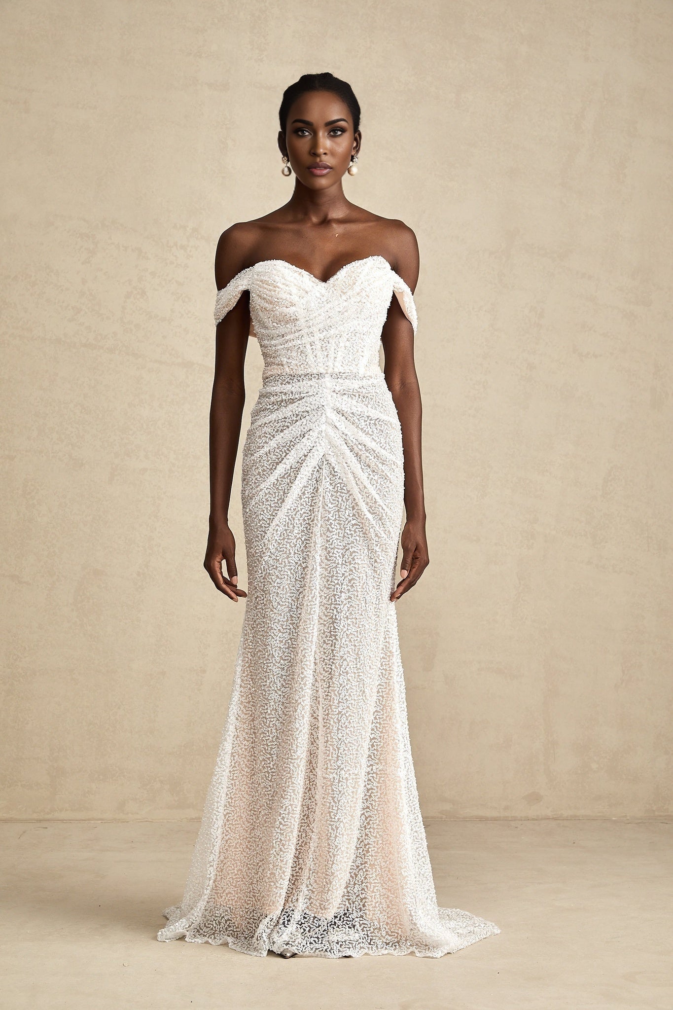 A white offshoulder maxi dress with embellishments named Margot featuring a long flowing skirt and decorative details on the bodice