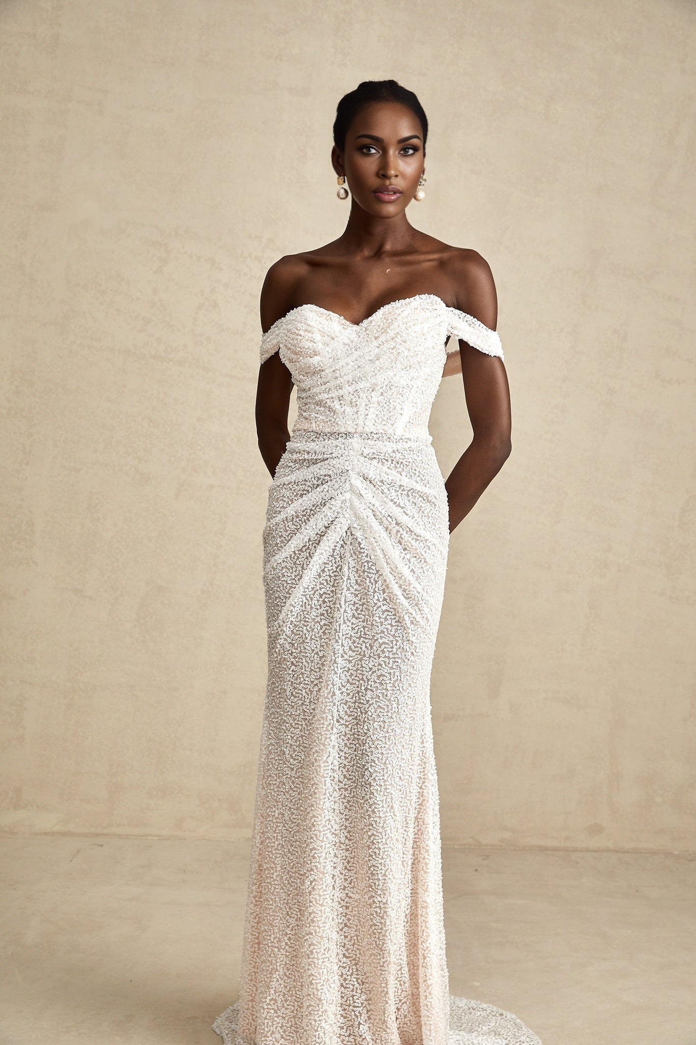 A white offshoulder maxi dress with embellishments named Margot worn by a model against a plain background