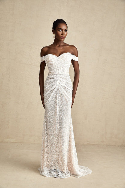 A white offshoulder maxi dress with embellishments worn by a model named Margot