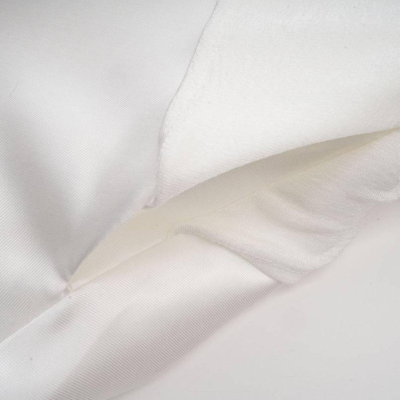 A white offshoulder maxi dress with panel detailing worn by a model standing against a plain background