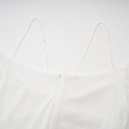 A white offshoulder maxi dress with panel detailing worn by a model standing against a plain background