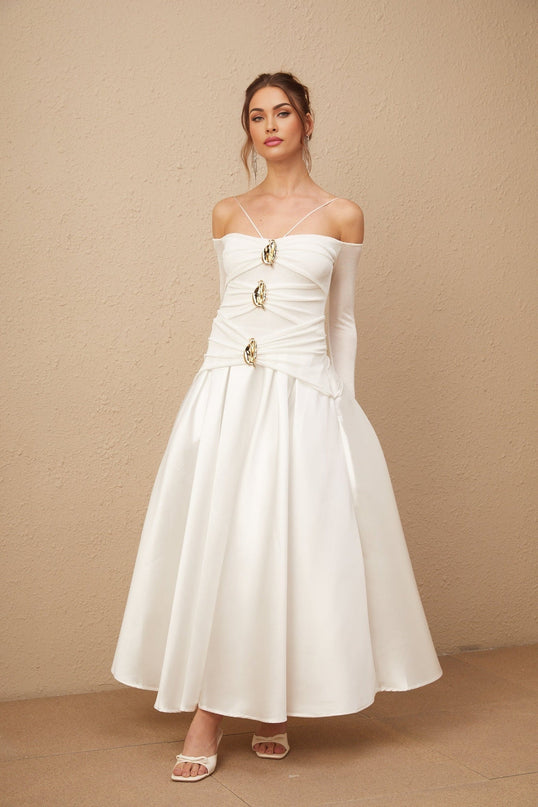 A white offshoulder maxi dress with panelled design worn by a model standing against a plain background