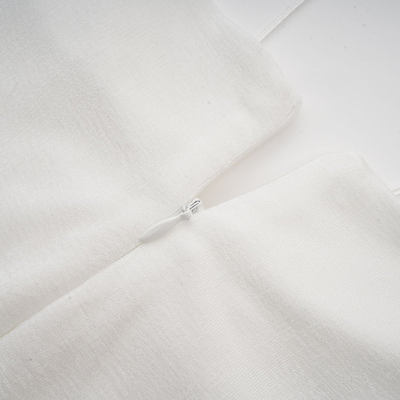 A white offshoulder maxi dress with panels worn by a model standing against a plain background