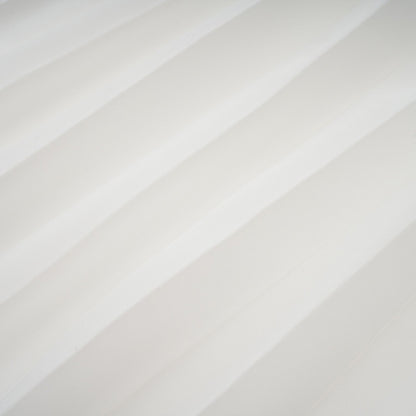 A white offshoulder maxi dress with pleated details and a flowing silhouette worn by a model named Vanessa