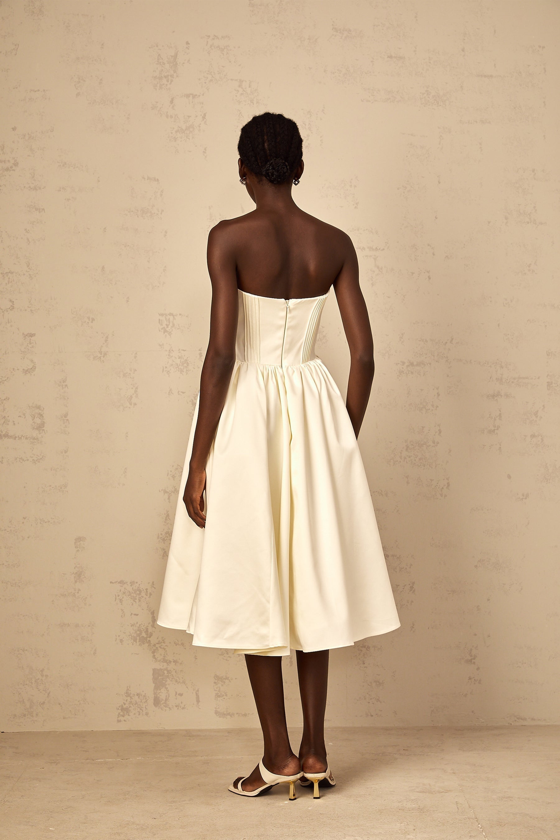 A white offshoulder midi dress for women with shirred detailing shown on a model against a plain background