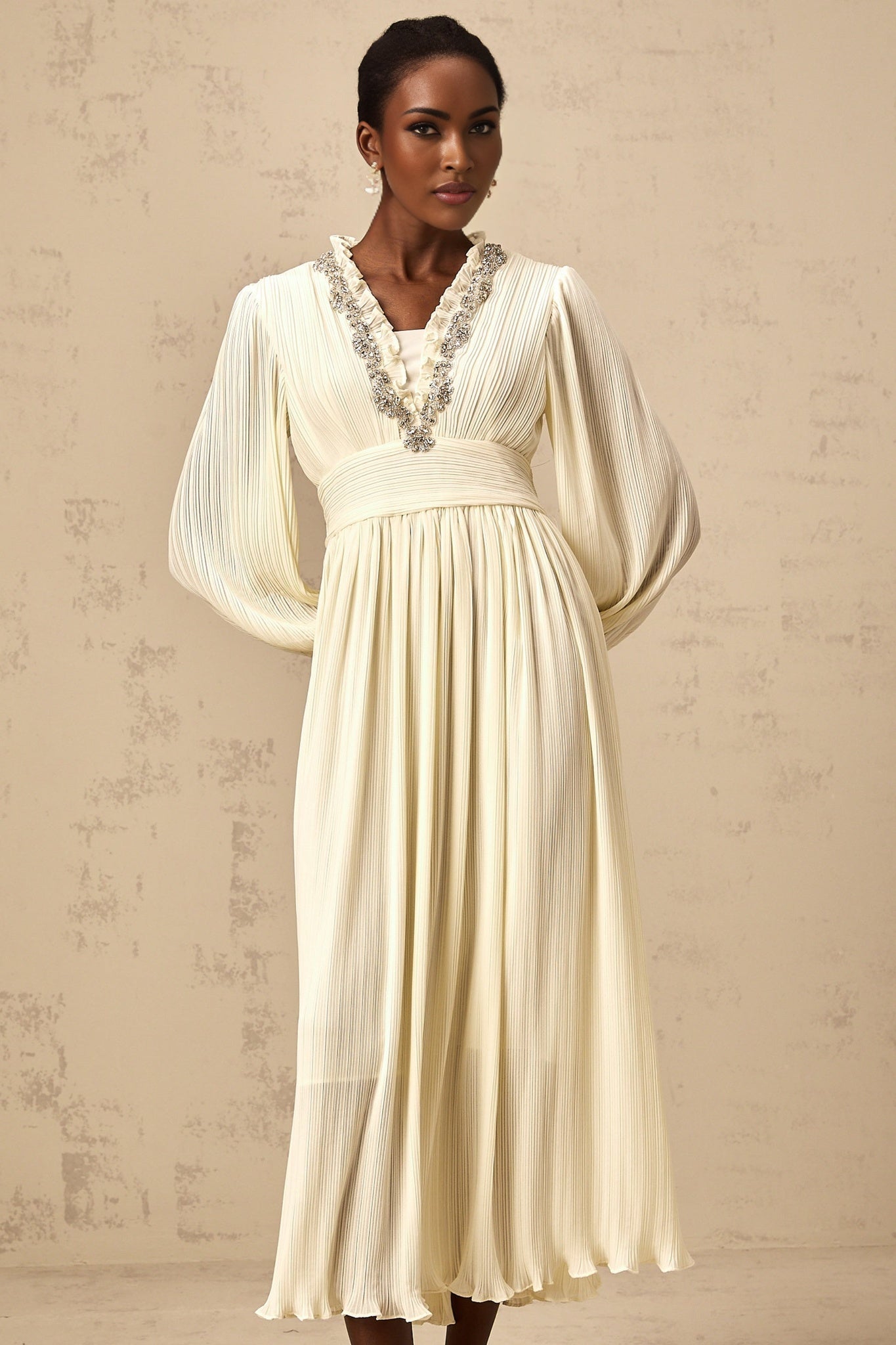A white pleated midi dress with crystal trim detailing along the neckline and waist named Yana