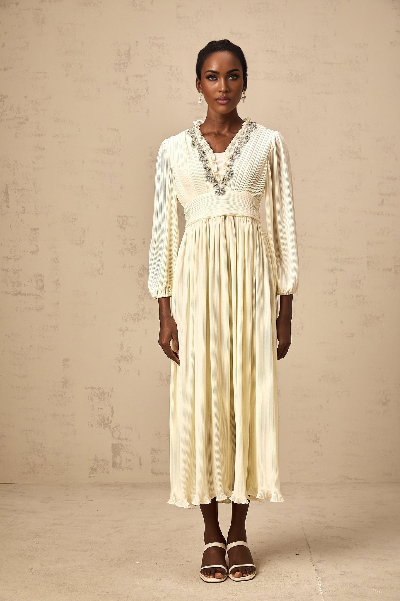 A white pleated midi dress with crystal trim detailing named Yana