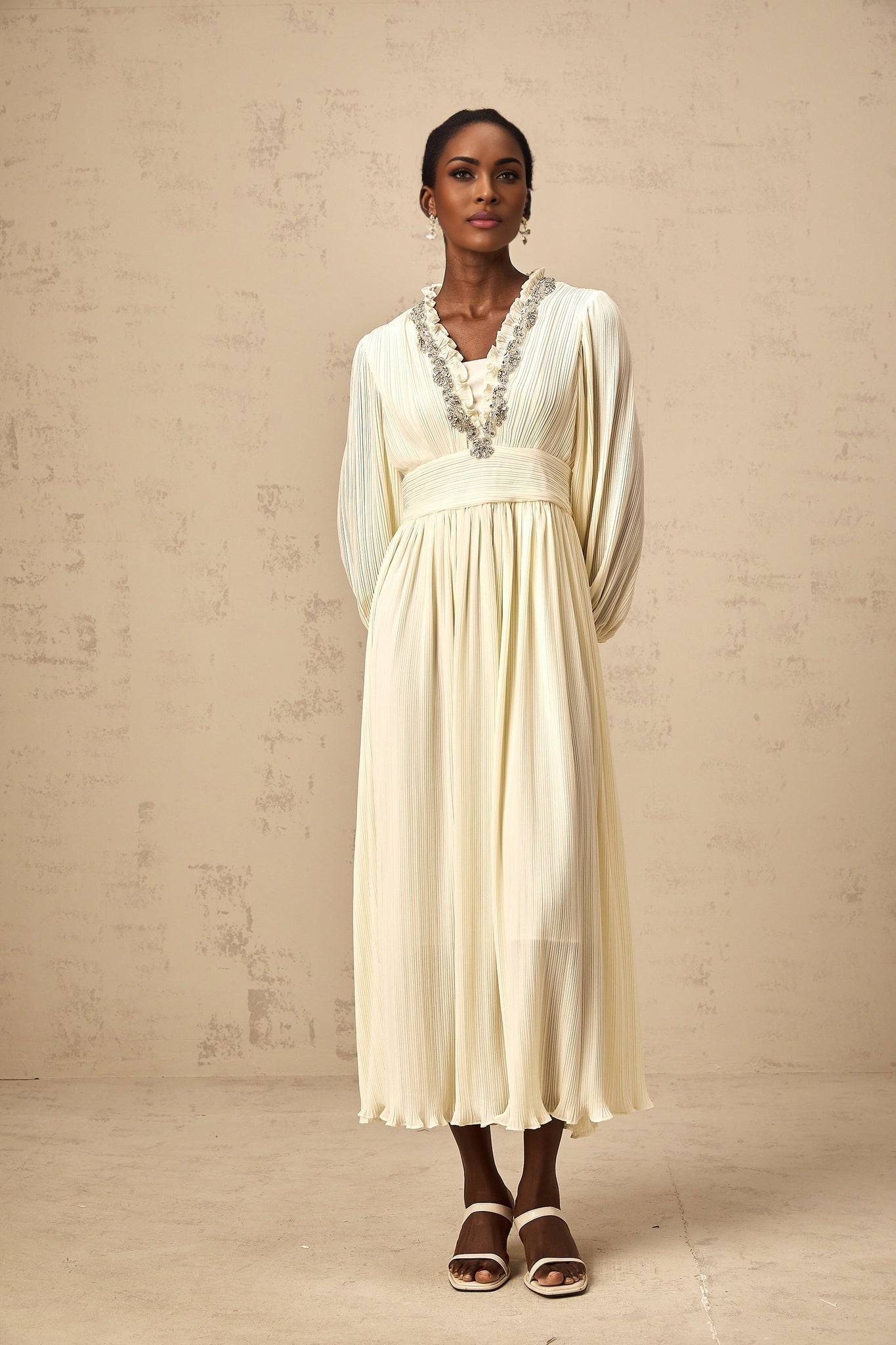 A white pleated midi dress with crystal trim detailing named Yana