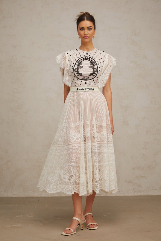 A white pleated midi dress with jacquard floral lace pattern named Phoebe featuring a delicate design and flowing silhouette
